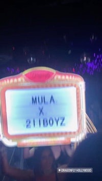 a woman holding up a sign that says mula x 21 boysz