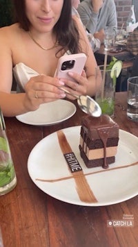 a woman taking a picture of a piece of chocolate cake