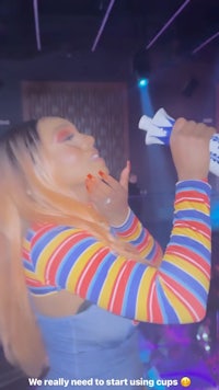 a woman in a striped shirt is holding a cup
