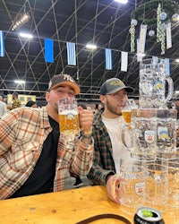 two men sitting at a table with beer mugs in front of them